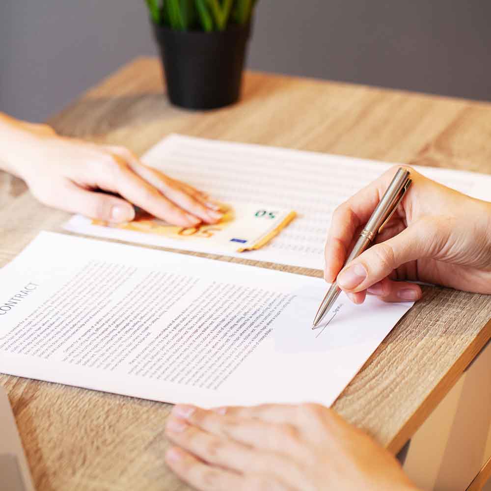 Client and attorney working at a desk signing a legal contract.